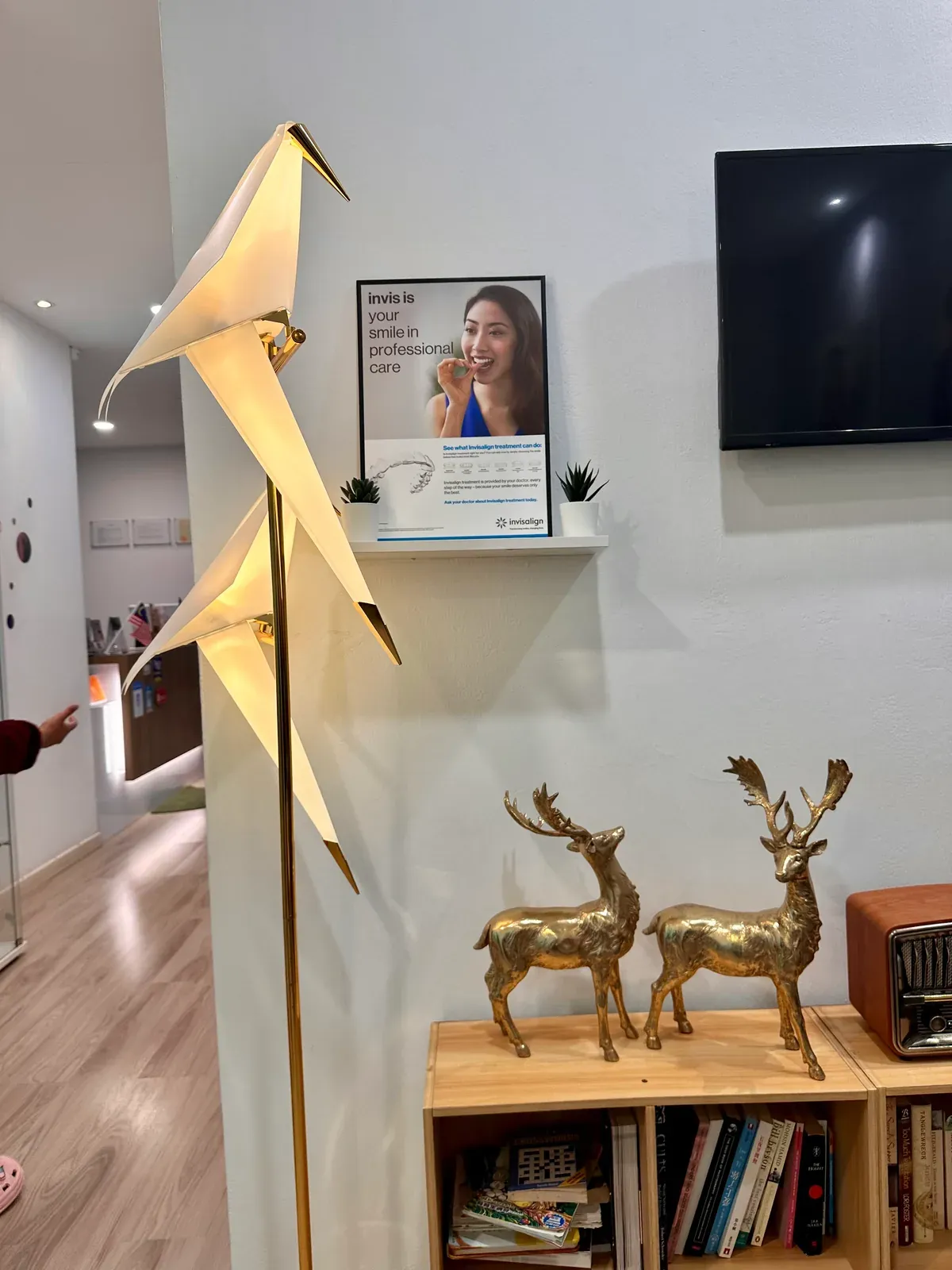 Reception decor at Lau & Su Partners Dental Bukit Jalil, with a gold origami crane, deer figurines and a shelf of books
